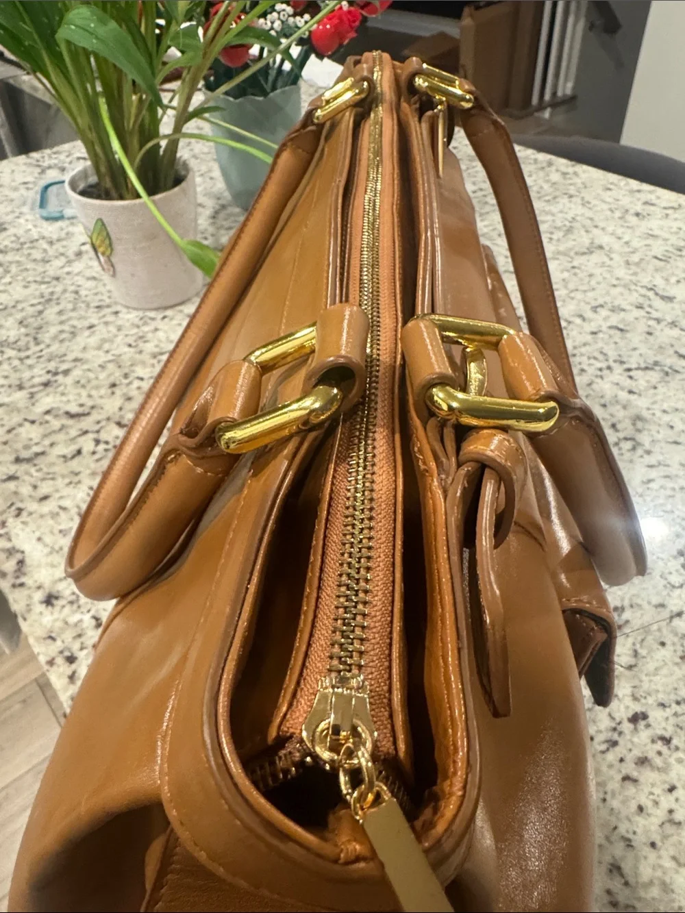 The Find Classic Tan Leather Weekender Travel Bag with Gold Hardware Buckle.